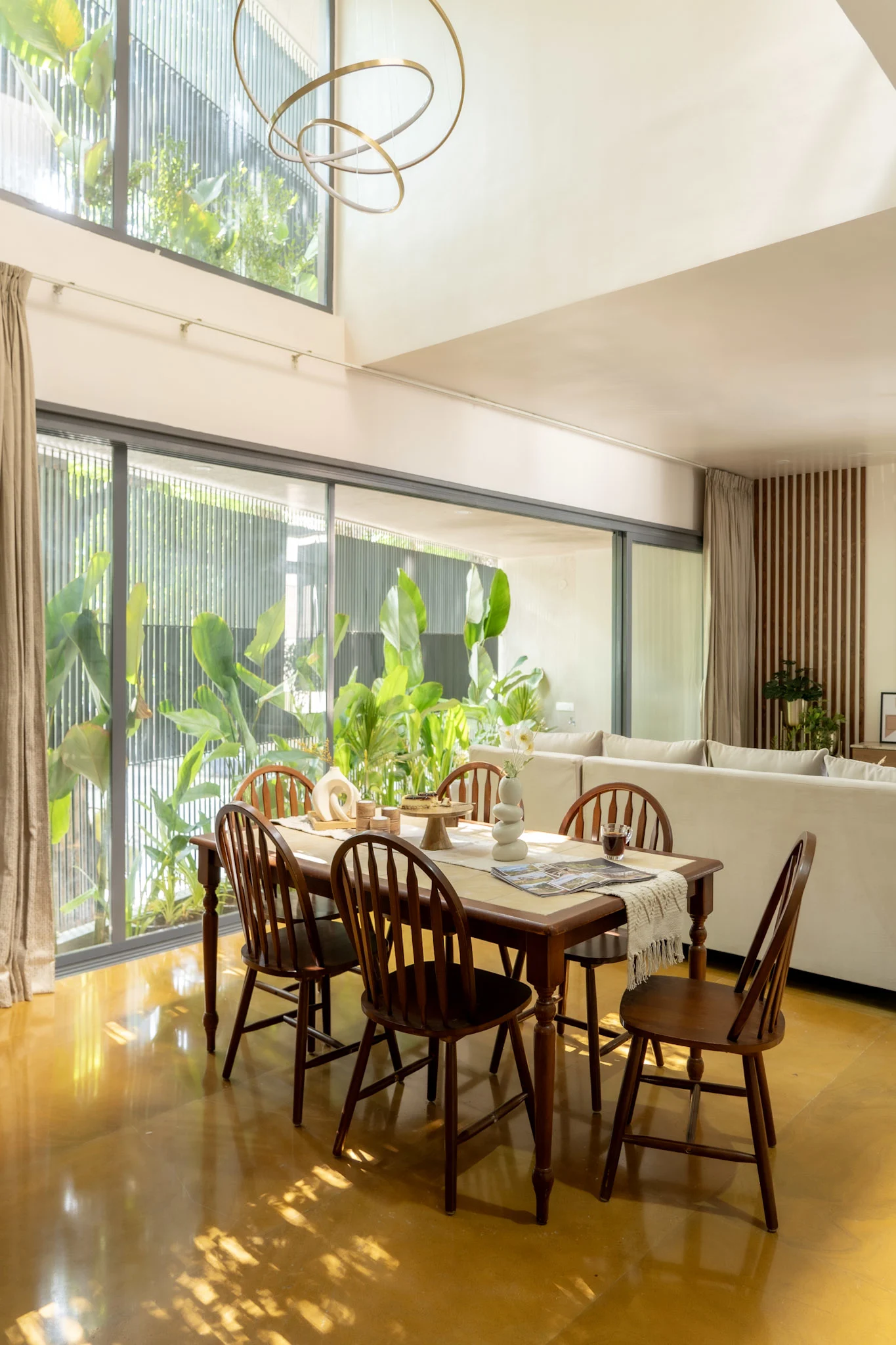 Double height dining area with wooden dining table and large glass facade in modern villa