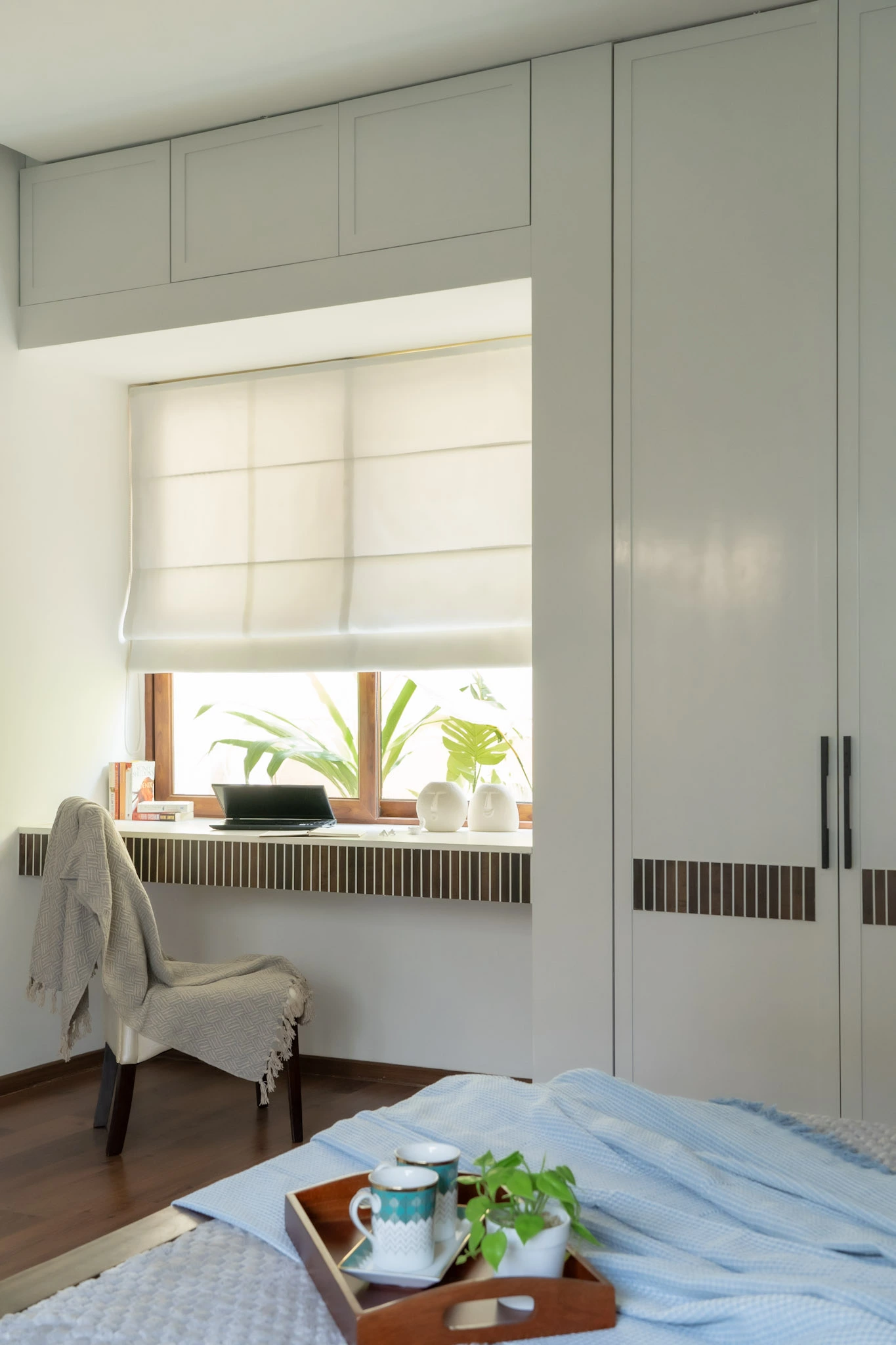 Luxury bedroom with white wardrobes, study corner, wooden flooring, and large window seating