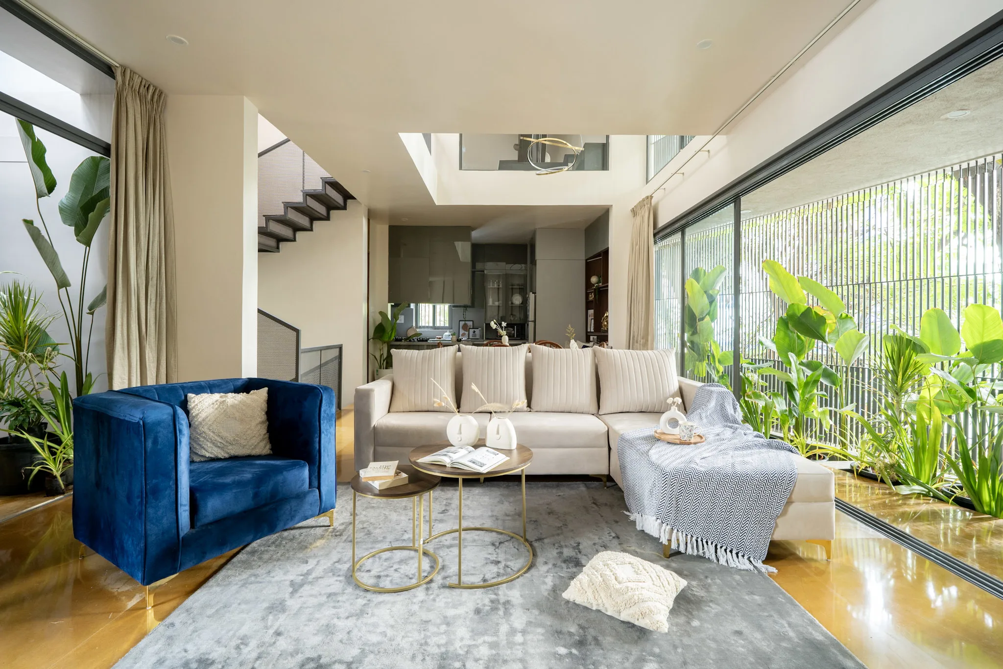 Modern living room interior with blue accent chair, beige sofa and indoor plants