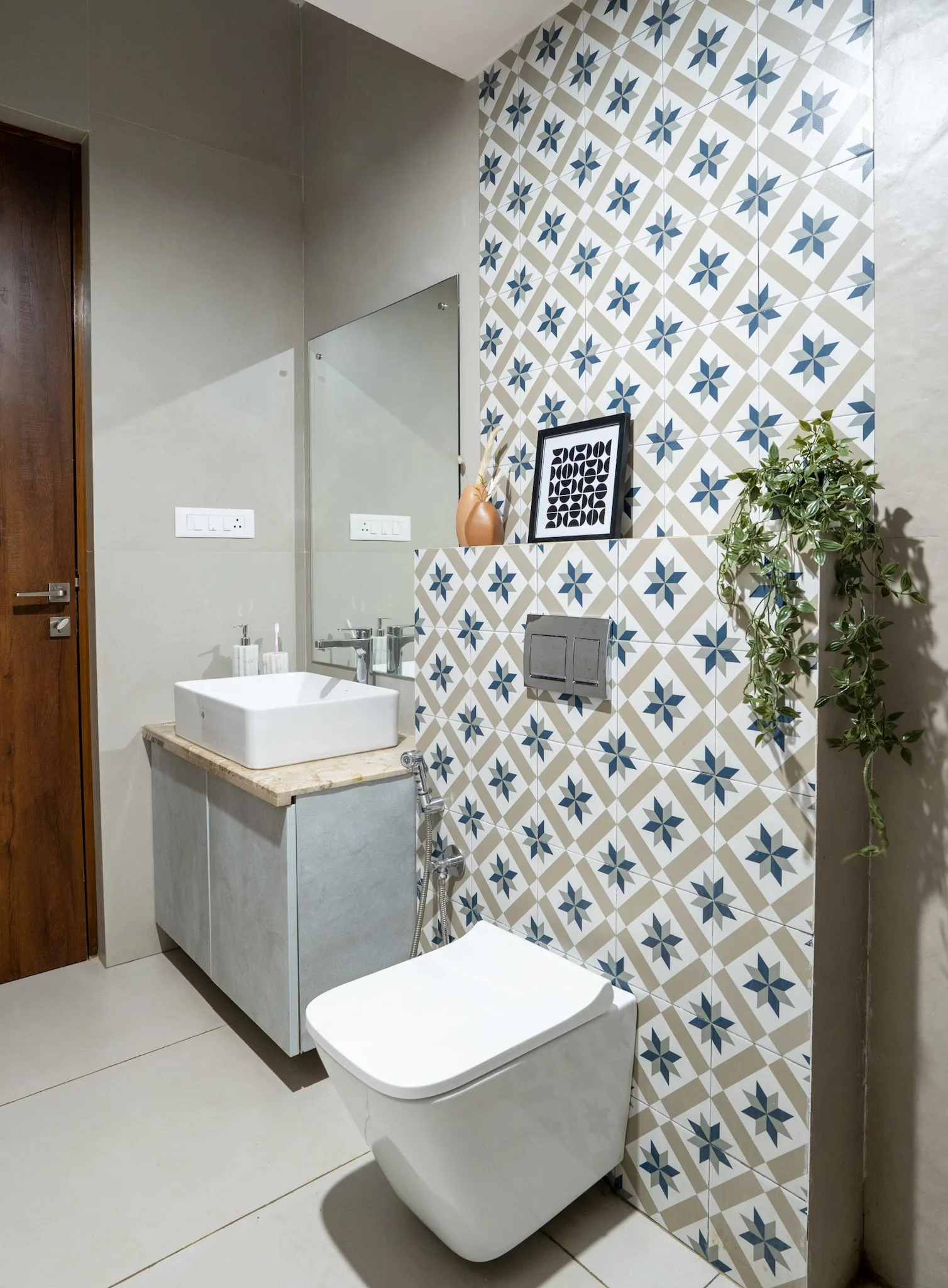 Modern bathroom with patterned wall tiles, wall mounted toilet and compact vanity unit