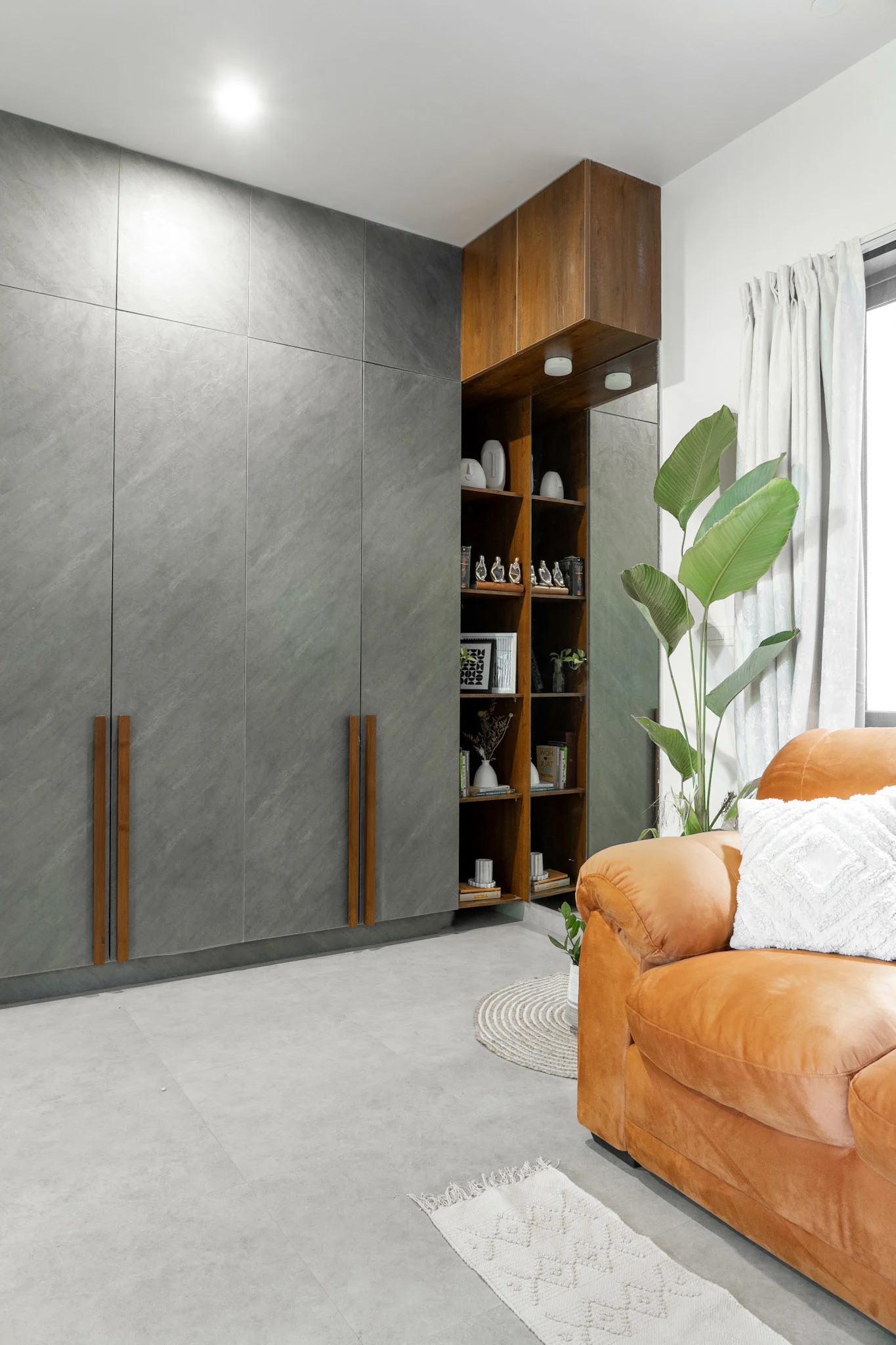 Grey wardrobe design with wooden shelves and orange accent sofa in modern bedroom
