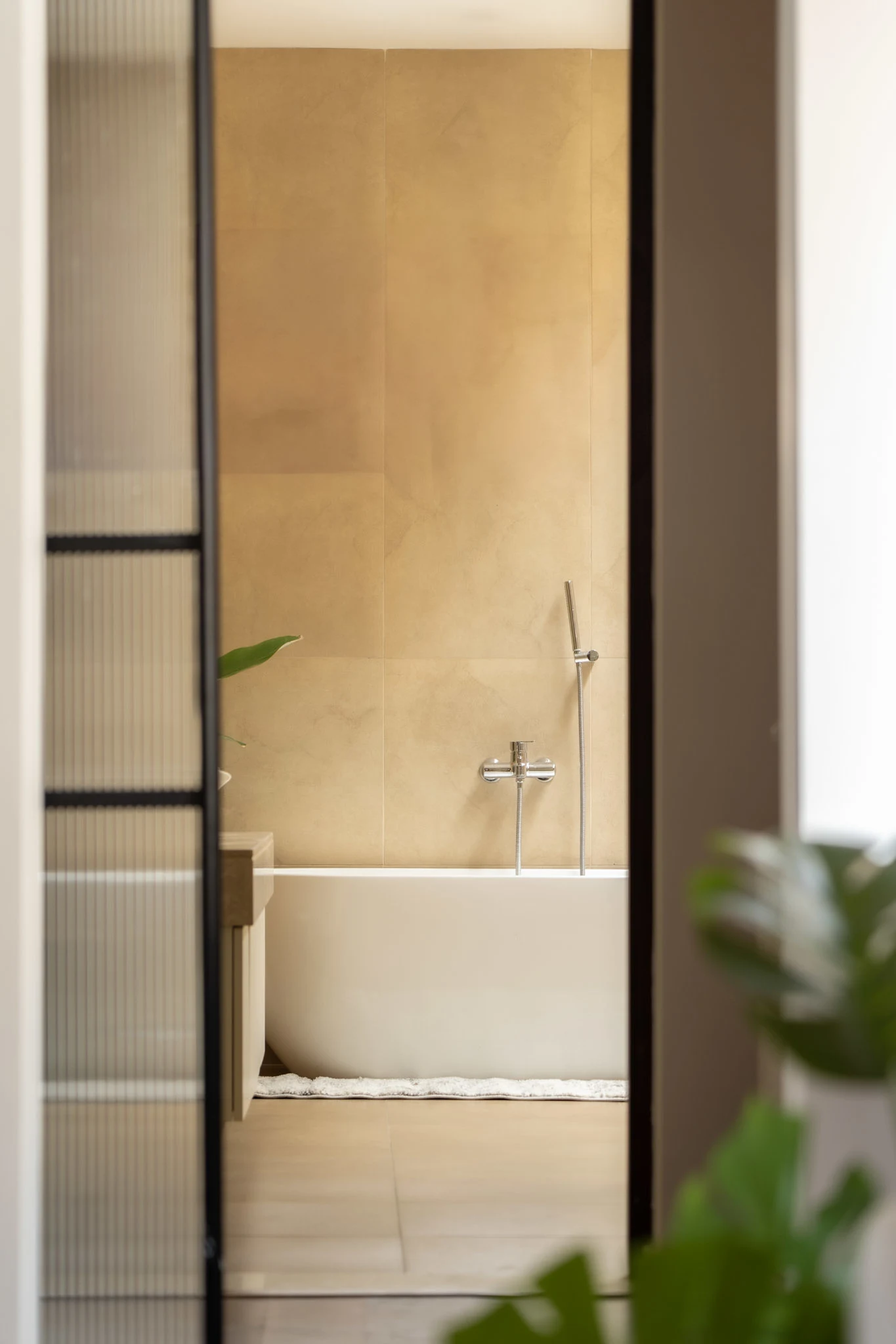 Minimal luxury bathroom with freestanding bathtub, beige wall tiles, and modern fittings