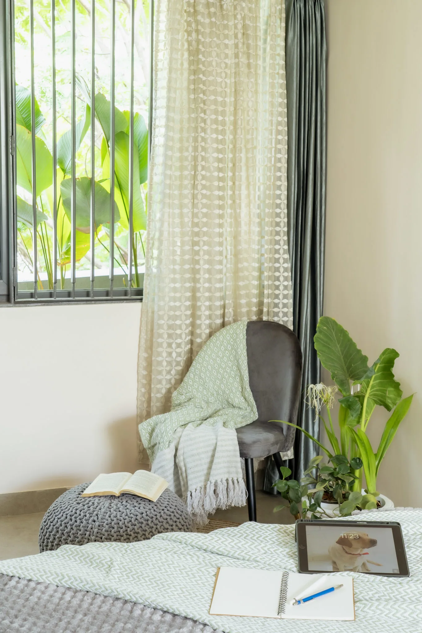 Cozy bedroom corner with indoor plants, reading chair, sheer curtains and natural daylight