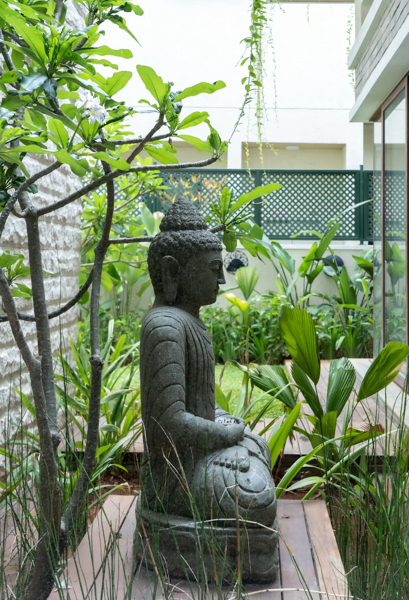 Contemporary villa landscape with Buddha sculpture, tropical plants, and private meditation garden design