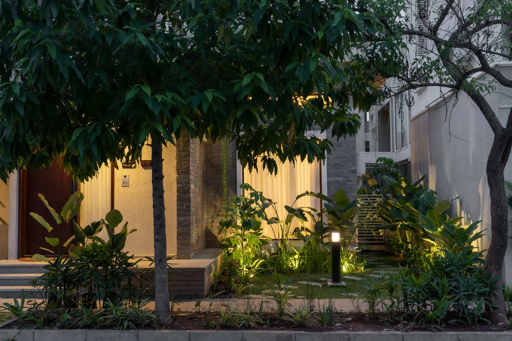 Luxury villa front landscape lighting design with tropical garden and modern outdoor seating area in Bangalore