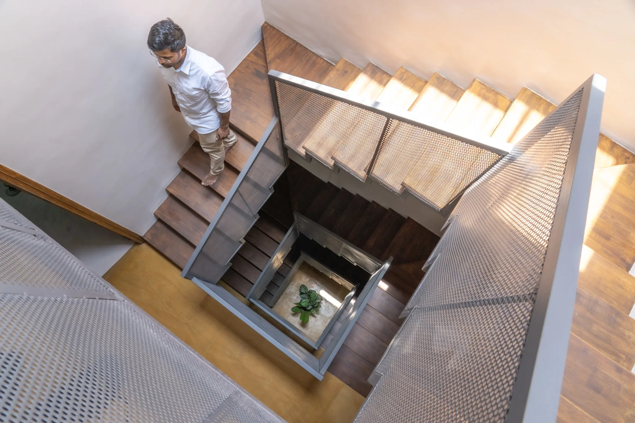 Modern staircase with wooden steps and perforated metal railing inside contemporary villa