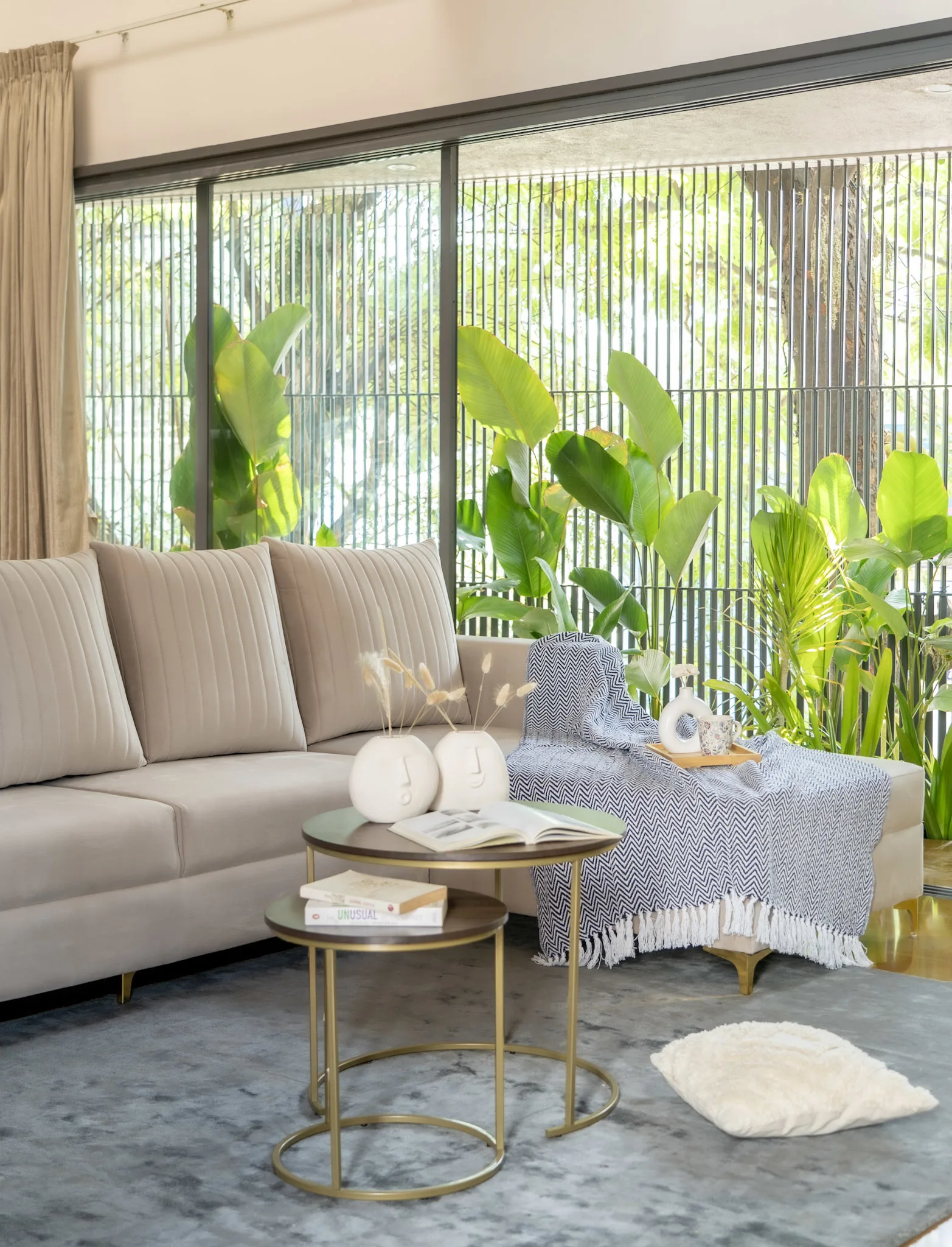 Contemporary living room with beige sofa, indoor plants and large glass windows