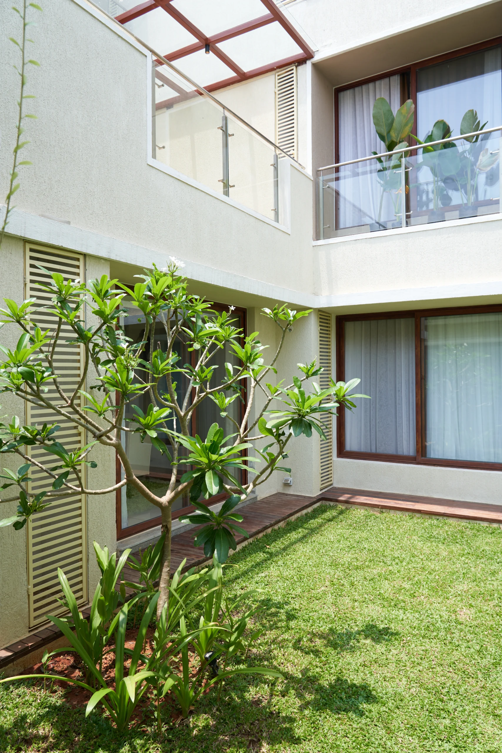 Modern villa backyard garden with outdoor seating, green lawn, tropical plants, and contemporary landscape design